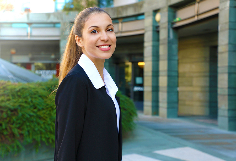 Smiling young woman in business dress in front of office