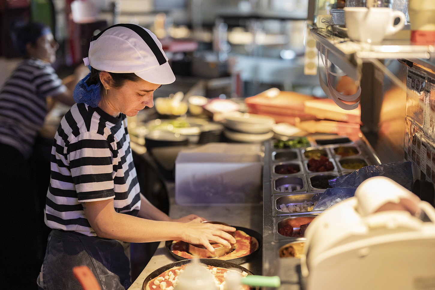 Restaurant worker prepares pizzas