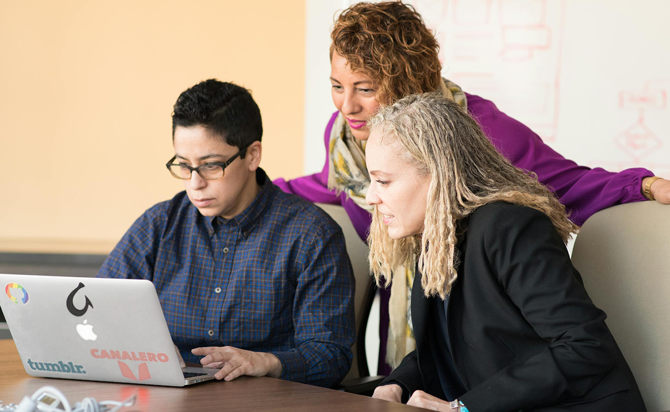 Three women look at laptop