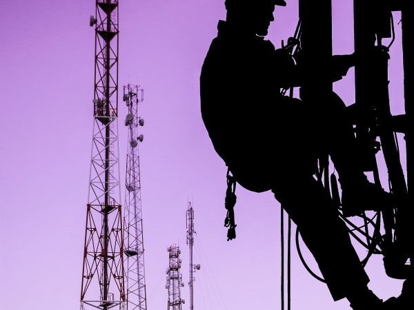 Electrical worker in silhouette climbing tower