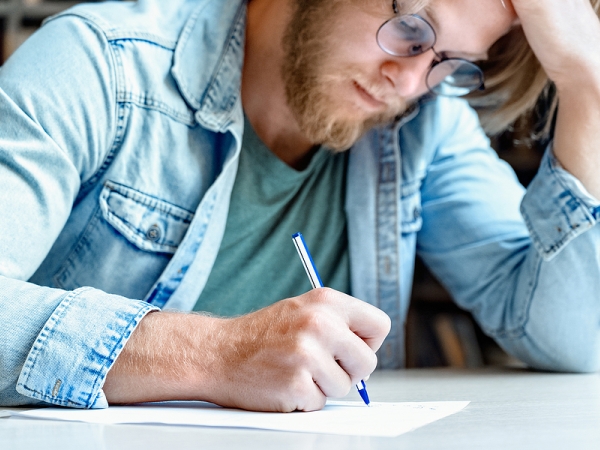 Adult white man in denim shirt fills out written evaluation