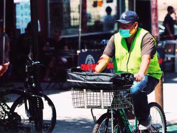Delivery bicylist wearing high-viz vest, ball cap and covid mask