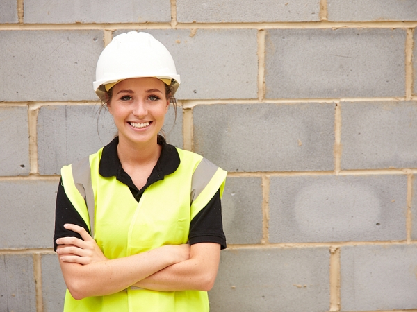 A construction worker standing by a brick building