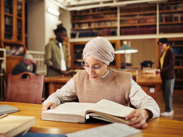 Woman in headscarf studies in library