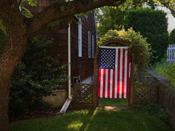 Backyard with U.S. flag hanging in archway while family celebrates Labor Day out of camera