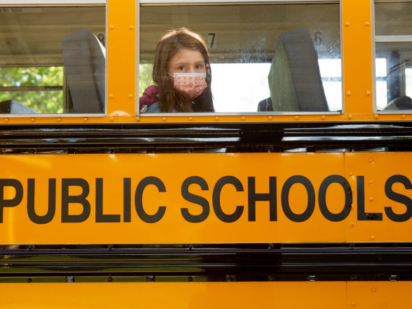 Girl with covid mask sits on a public school bus