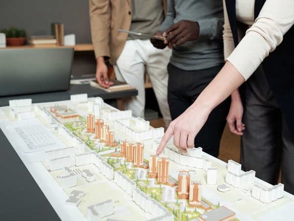 Woman points at building in a development model while others look on
