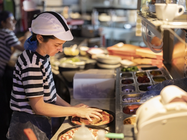 Restaurant worker prepares pizzas