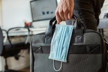 Man carrying face mask and computer bag back to work