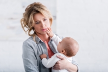 Tired mother holding baby, with baby clawing at mom's face, as they do